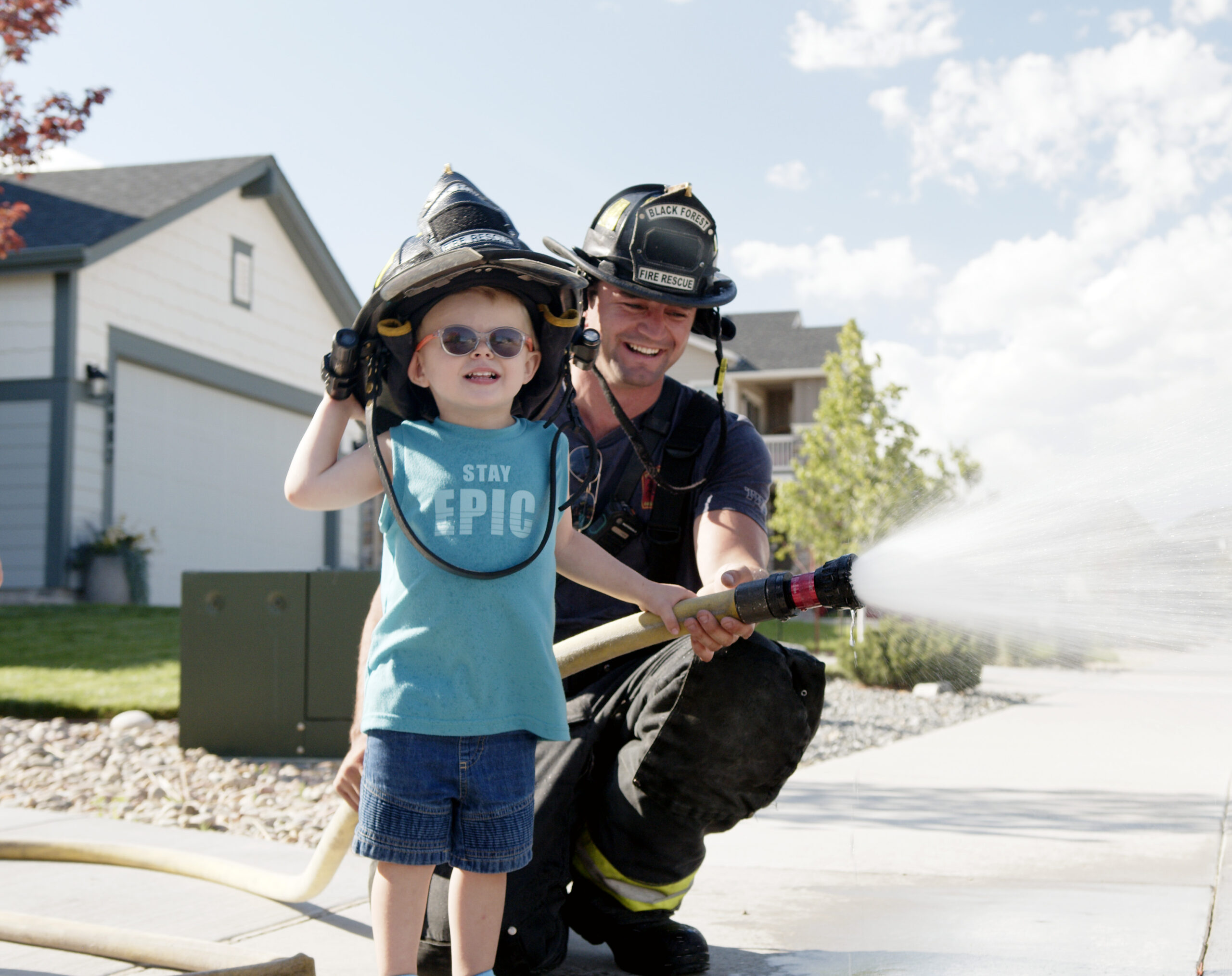 Firefighter teaching a child how to use fire hose